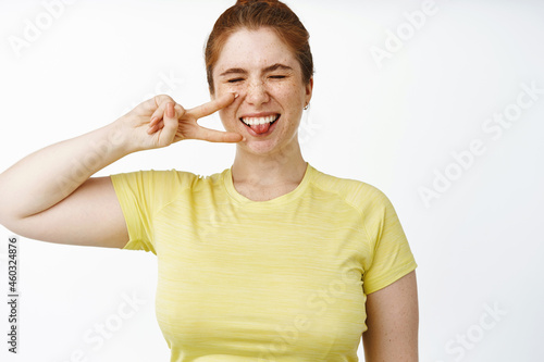 Wallpaper Mural Happy young chubby woman wearing sport clothing, showing peace sign and laughing, smiling and looking positive, white background Torontodigital.ca