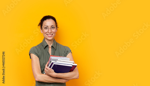 Young student woman smiling holding books and wearing