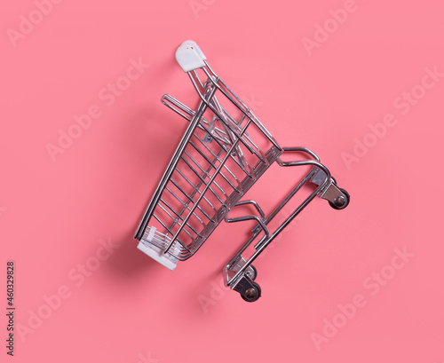 Close-up of shopping trolley on pink background,empty shopping cart