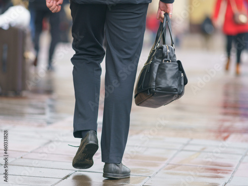 Man on the Moscow city street in the city center. He holding leather bag. Moving ahead. Lifestyle concept. Back, rear view. Defocused background