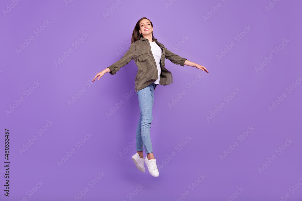 Full length body size photo smiling woman jumping up in stylish outfit isolated pastel purple color background Full length body size photo smiling woman jumping up in stylish outfit isolated pastel purple color background