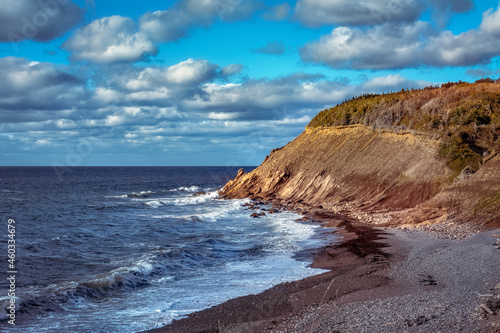 Late in the Day - Evening is approaching the rugged coast of Cape Breton. The sun shines upon the face of a cliff while waves of the cool waters of the Atlantic Ocean land upon the rocky beach.