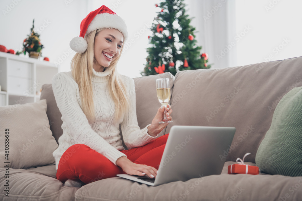 Full length body size photo blonde woman drinking champagne sitting on sofa got video call on laptop Full length body size photo blonde woman drinking champagne sitting on sofa got video call on laptop