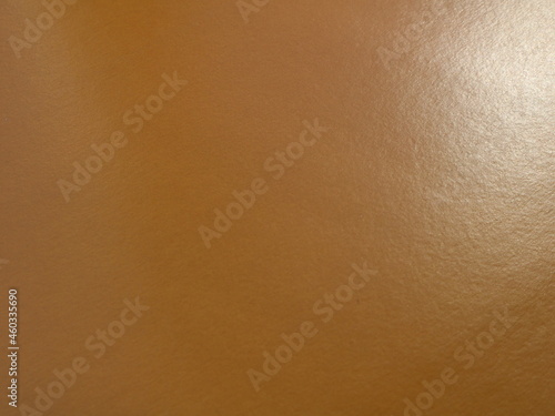 brown smooth glossy material with blank copy space, paper or cardboard with a characteristic ribbed texture and a spot of light on the surface, milk chocolate shade empty backdrop