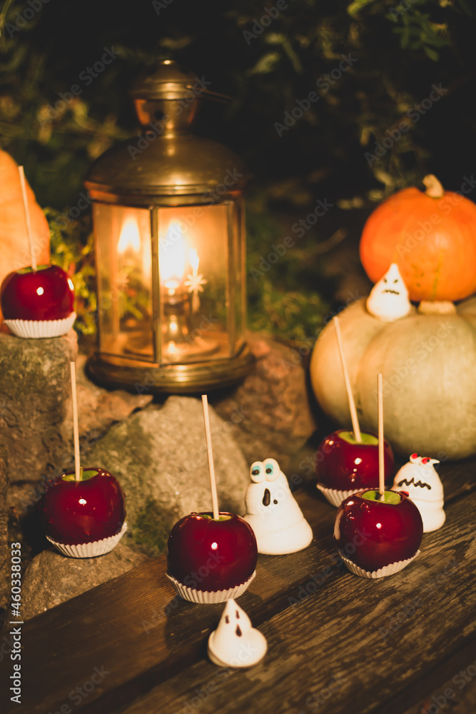An enchanting outdoor Halloween scene showcasing candy-coated apples and meringue ghouls, complemented by a rustic lantern's soft glow and seasonal pumpkins.