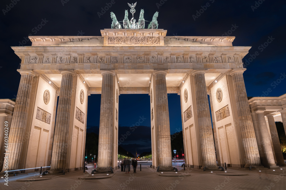 Brandenburg Gate symbol of Cold War stands strong illuminated against night sky.