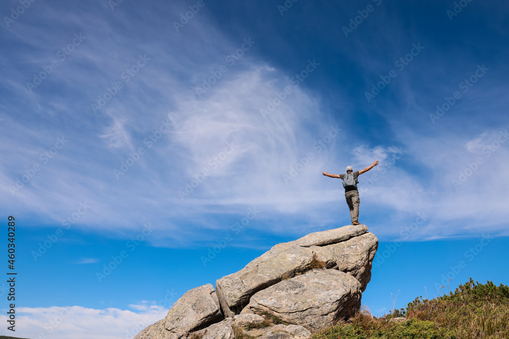 Man on rocky peak, back view. Space for text Man on rocky peak, back view. Space for text