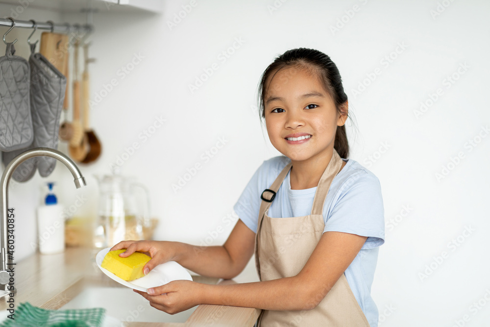 Little housekeeper. Happy asian girl helping mother in kitchen, washing and wiping dishes, standing in kitchen Little housekeeper. Happy asian girl helping mother in kitchen, washing and wiping dishes, standing in kitchen