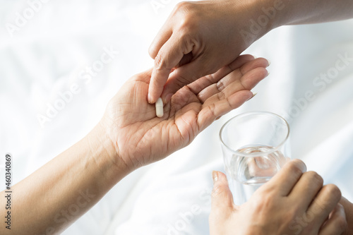 Close up of nurse hand putting white pill into patient hand.Sick female holding glass for taking medicines  antidepressant  painkiller or antibiotic.Pharmacy and healthcare concept
