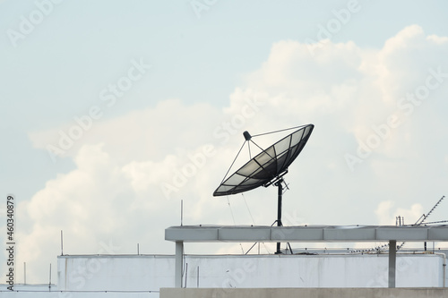 Satellite dish on building deck roof.Satellite receiver on sky and clouds background.