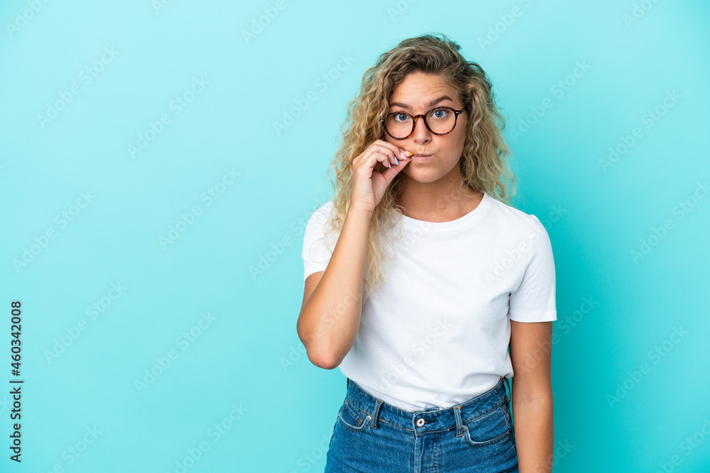 Girl with curly hair isolated on blue background showing a sign of silence gesture Girl with curly hair isolated on blue background showing a sign of silence gesture