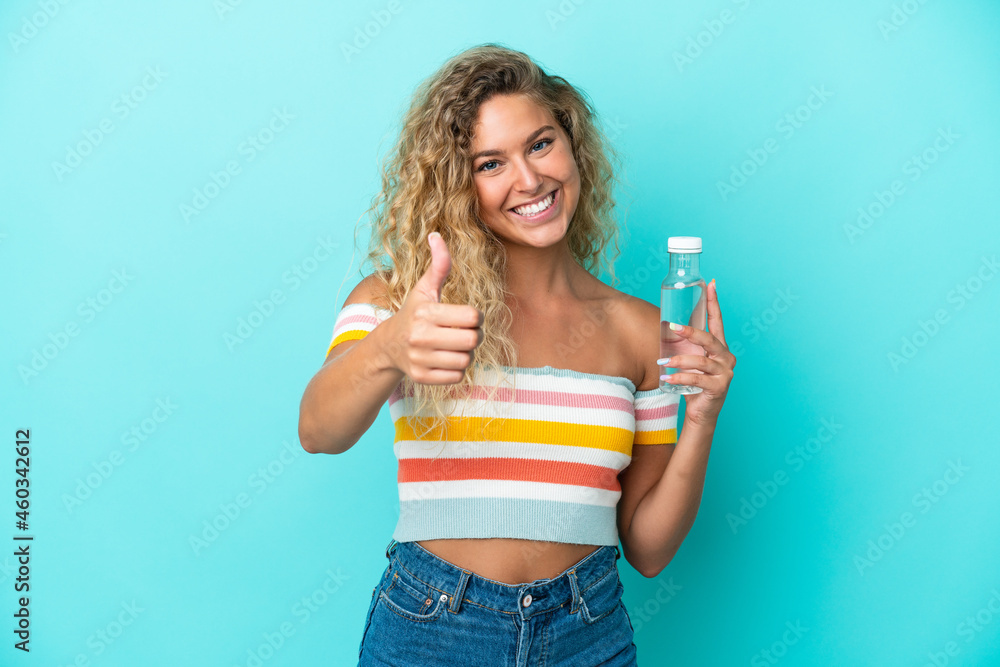 Young blonde woman with a bottle of water isolated on blue background with thumbs up because something good has happened Young blonde woman with a bottle of water isolated on blue background with thumbs up because something good has happened