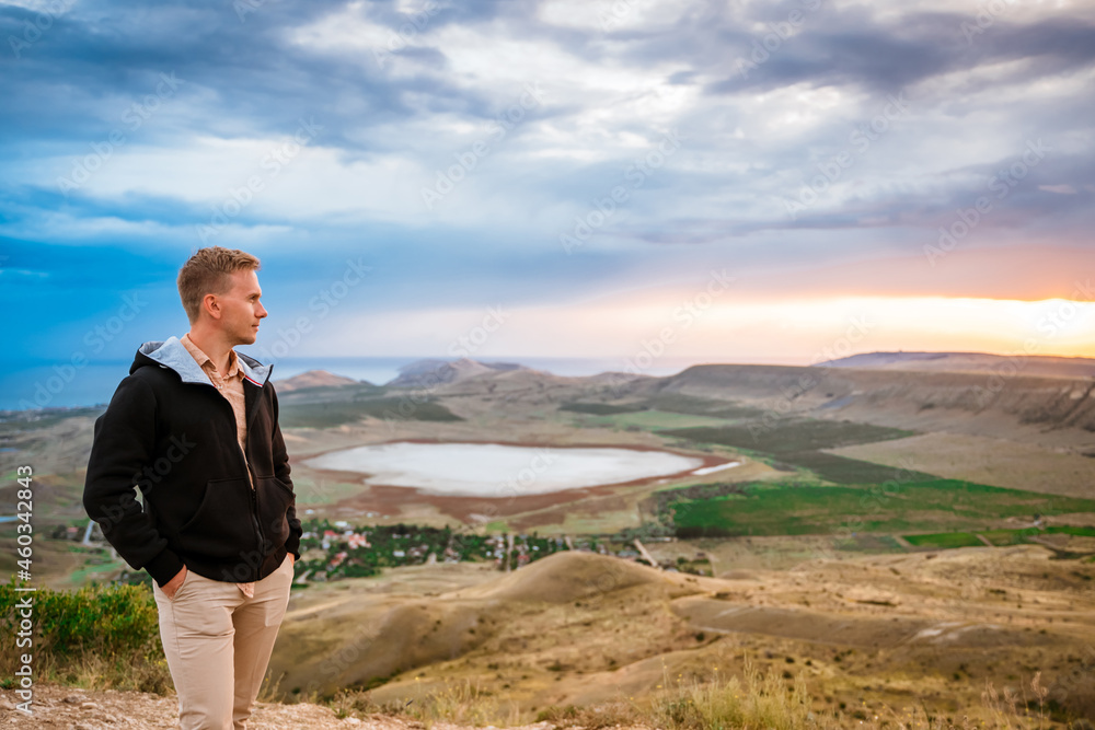 A young man conquered the top of the mountain at dawn. Beautiful mountain landscape with a slope. The concept of enjoying nature. A young man conquered the top of the mountain at dawn. Beautiful mountain landscape with a slope. The concept of enjoying nature.