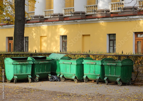 Mobile plastic green garbage containers at the yellow wall of the old building, Admiralteysky Passage, St. Petersburg, Russia, October 2021 © Станислав Вершинин
