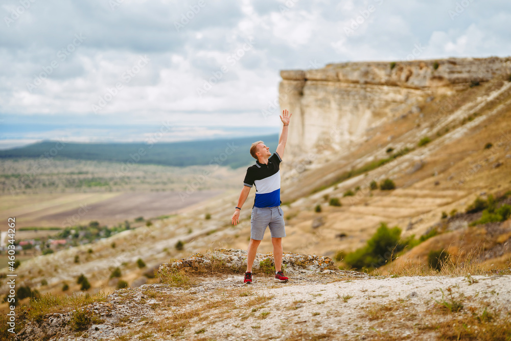 Handsome young blond man on a cliff overlooking the rustic landscape, White rock in Crimea