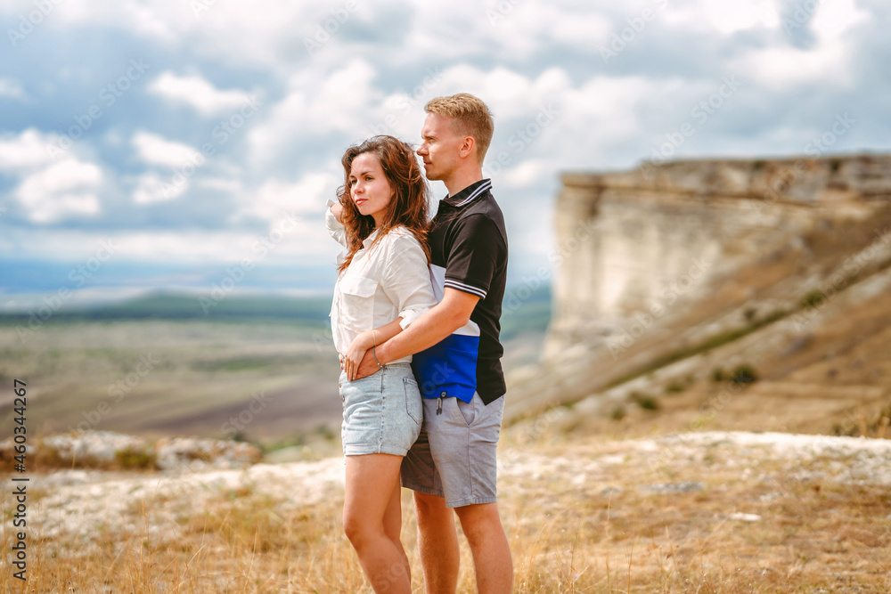 A man and a woman in love embrace on the edge of a cliff with a view of the White Rock and the surrounding area in the Crimea. The concept of joint travel. A man and a woman in love embrace on the edge of a cliff with a view of the White Rock and the surrounding area in the Crimea. The concept of joint travel.