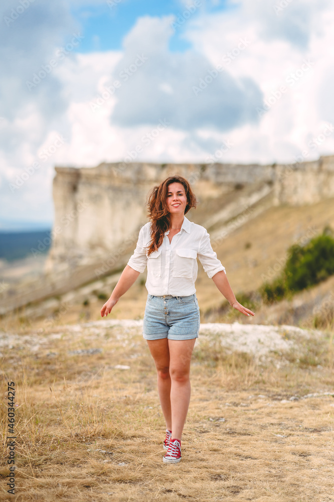 Portrait of a beautiful young woman in a white shirt on the edge of a cliff with an endless panorama, White Rock in the Crimea. The concept of travel Portrait of a beautiful young woman in a white shirt on the edge of a cliff with an endless panorama, White Rock in the Crimea. The concept of travel