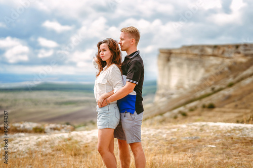 A man and a woman in love embrace on the edge of a cliff with a view of the White Rock and the surrounding area in the Crimea. The concept of joint travel.