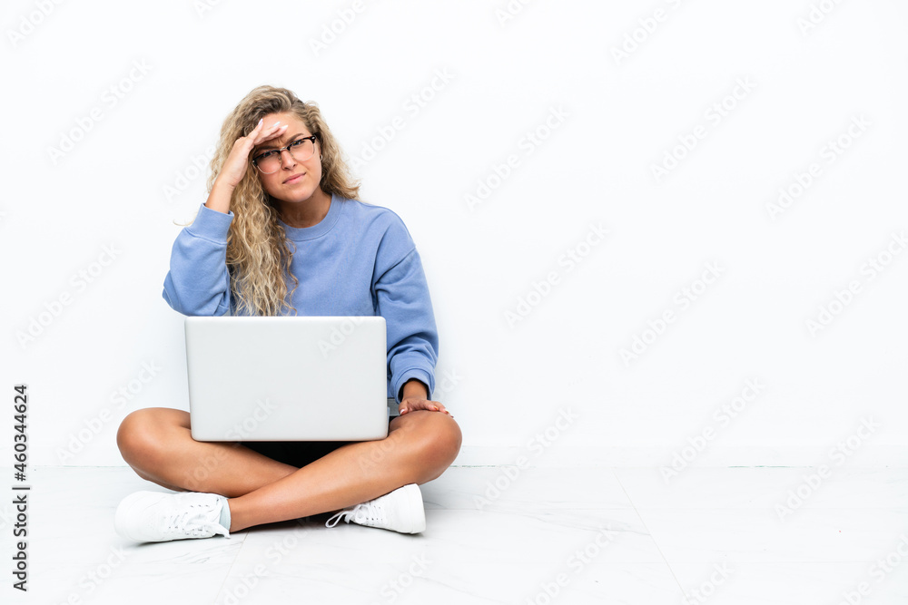 Girl with curly hair with a laptop sitting on the floor looking far away with hand to look something Girl with curly hair with a laptop sitting on the floor looking far away with hand to look something
