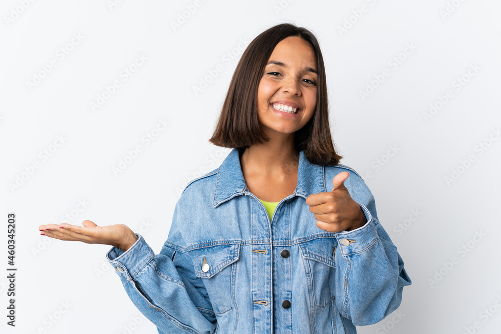 Young latin woman isolated on white background holding copyspace imaginary on the palm to insert an ad and with thumbs up Young latin woman isolated on white background holding copyspace imaginary on the palm to insert an ad and with thumbs up