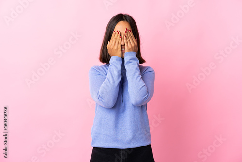 Young latin woman isolated on pink background covering eyes by hands