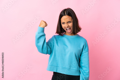 Young latin woman isolated on pink background celebrating a victory