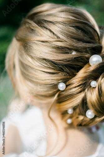 the bride's hairstyle is a bun. rear view. Hair decoration in the form of pearl beads. Preparation for the wedding.
