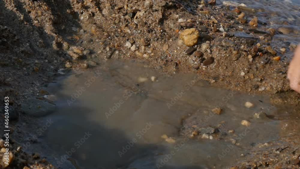 little hands of a teenager are playing in the sand on the beach, digging a hole from the sand. Close-up. Slow motion little hands of a teenager are playing in the sand on the beach, digging a hole from the sand. Close-up. Slow motion