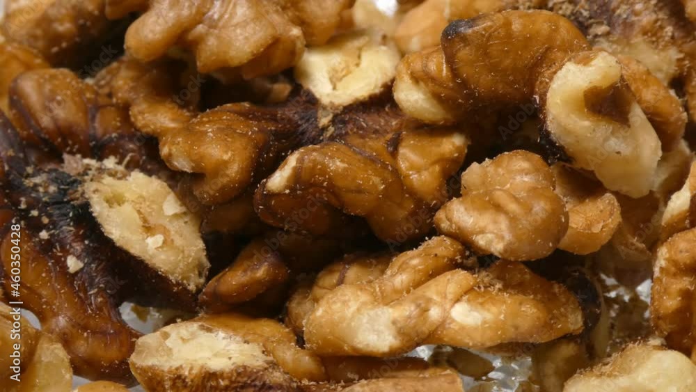 Saw toothed grain beetle wandering in old walnuts, 4k detail, nuts rotating on plate Saw toothed grain beetle wandering in old walnuts, 4k detail, nuts rotating on plate