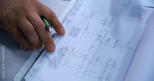 A plant specialist in the control room, checks the current settings in the operating equipment in the diagram log (design documentation) 