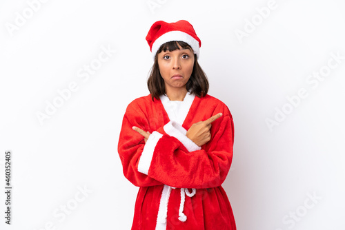 Young mixed race woman disguised as Santa Claus isolated on white background pointing to the laterals having doubts