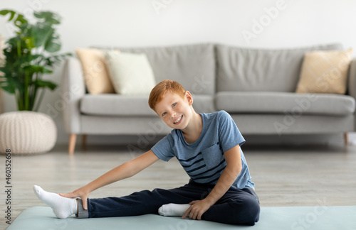 Cute kid stretching on fitness mat at home