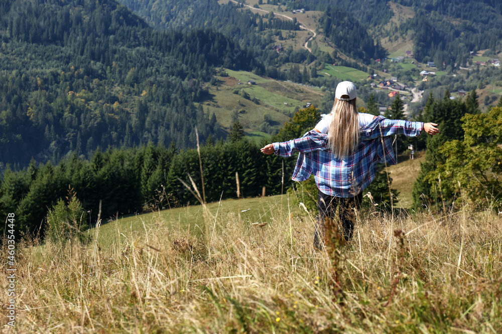 Woman enjoying picturesque landscape from top of hill, back view. Space for text