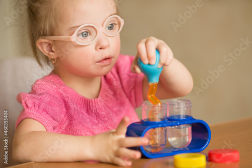 Girl with Down syndrome pours water by means of enema tubes in a test tube