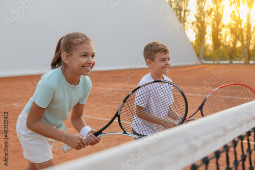 Happy children playing tennis on court outdoors © New Africa