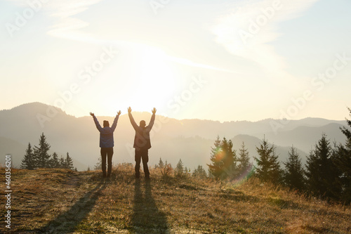 Couple enjoying sunrise in mountains, back view. Space for text