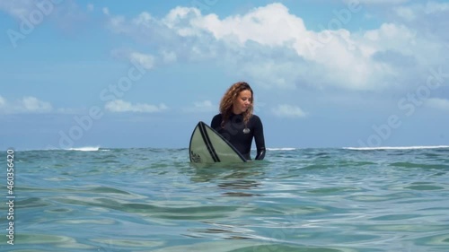 Video footage of surfer girl on white surf board in blue ocean pictured from the water in Bali