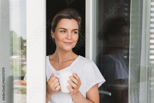 Beautiful woman with a cup of hot coffee looking into the window Free Download Beautiful woman with a cup of hot coffee looking into the window - GFXLoad