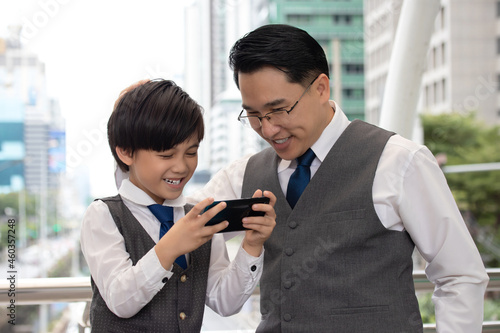 Asian businessman in a gray suit is teaching his son to learn business from an early age.