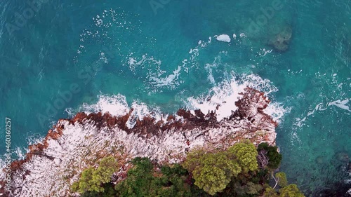 Drone shooting from top to bottom of waves washing the rocky shore. A bird's eye view of the shore and the sea. photo