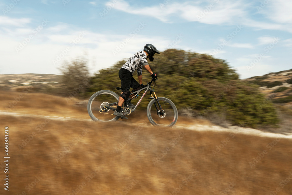 Professional bike rider during downhill ride on his bicycle in mountains