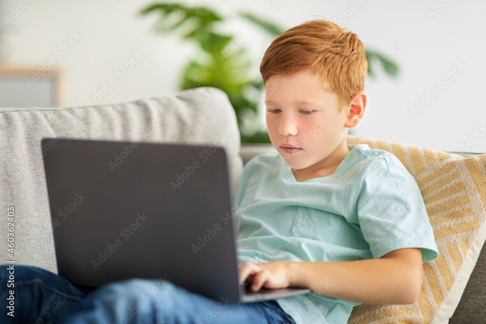 Redhead boy using laptop, playing online video game Redhead boy using laptop, playing online video game