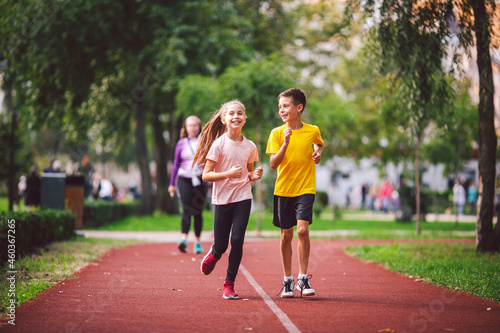 Child fitness, twins kids running on stadium track in city park , training and children sport healthy lifestyle. Outdoor activities by running make the child's body healthy and experience enriched