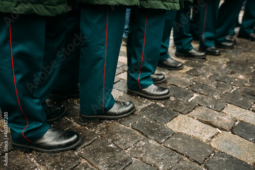 Military boots on the paving stones. Military parade, black boots, green uniform, large frame of shoes. Men's feet in boots