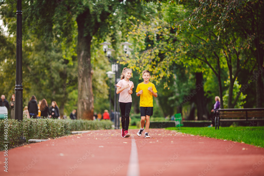 Fototapeta premium Kids run. Healthy sport. Child sport, heterosexual twins running on track, fitness. Joint training. Running training outdoor brother and sister pre-teen. Jogging with friend. Children athletes