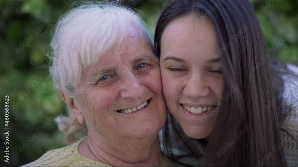 Beautiful teen girl huggimg and kissing her grandmother smiling, slow motion Beautiful teen girl huggimg and kissing her grandmother smiling, slow motion
