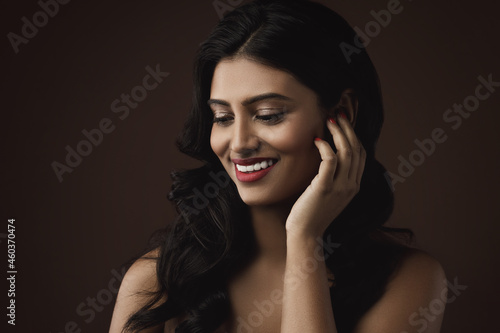 Indian woman with beautiful makeup and hairstyle on brown background