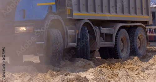 At the construction site of a plant under construction, a large, powerful, multi-axle cargo truck is driving in reverse to the place of loading 