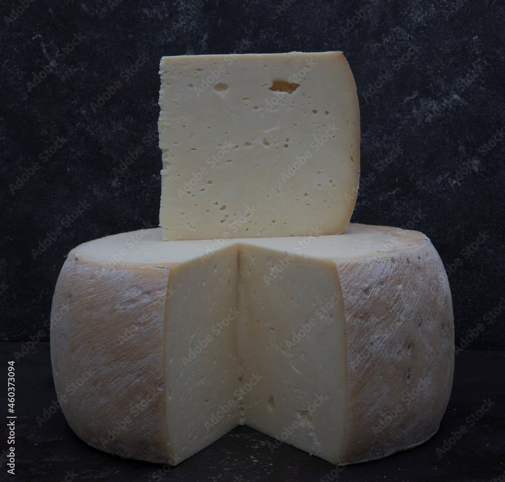 Old cheddar cheese. Wheel aged cheese. Aged cheddar cheese wheel on