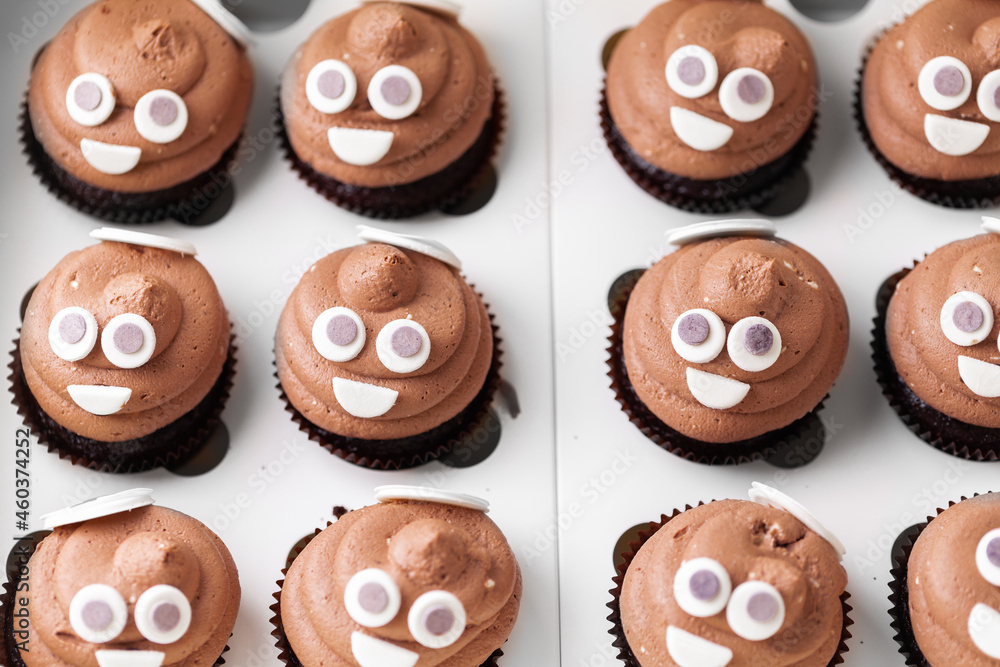 Set of cupcakes in the white gift box. Chocolate cupcake with brown cream cheese top decorated with mastic smiley face Set of cupcakes in the white gift box. Chocolate cupcake with brown cream cheese top decorated with mastic smiley face